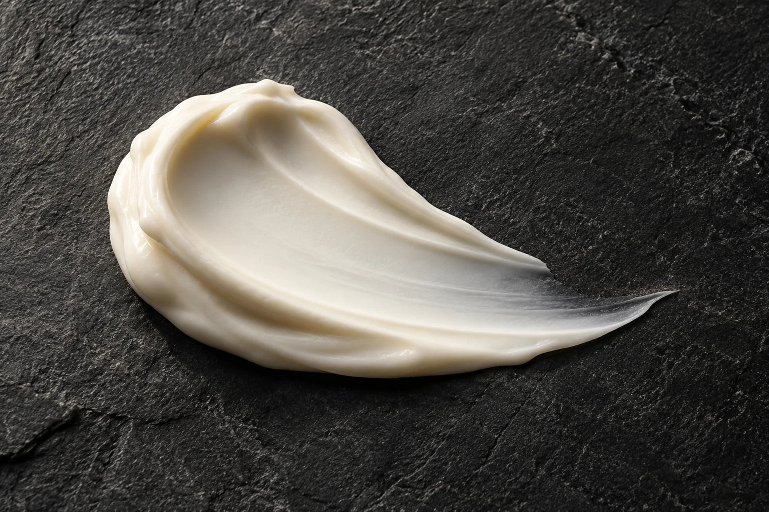 Illustrative ivory moisturizer texture on charcoal stone